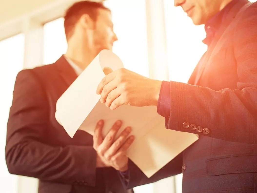Two men wearing a suit viewing and flipping a packet of papers. Two men wearing a suit viewing and flipping a packet of papers.