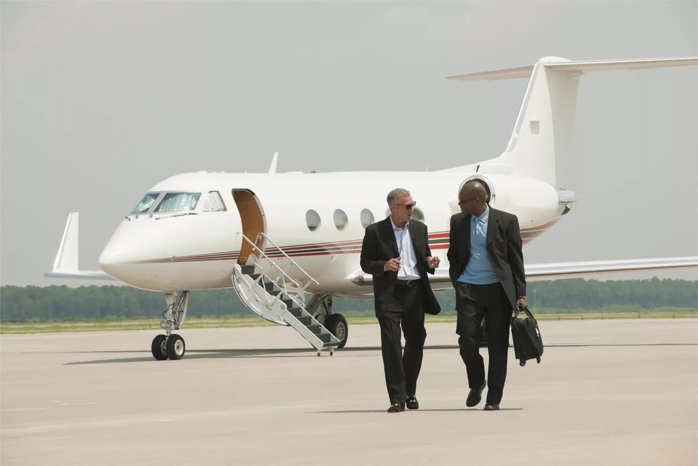 Two people walking on the runway, away from a plane in the background. Two people walking on the runway, away from a plane in the background.