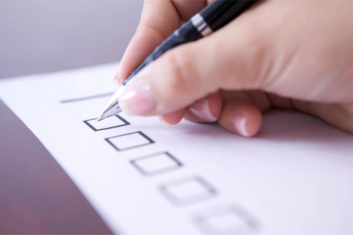 A near-focus view of a hand filling out checkboxes on a paper. A near-focus view of a hand filling out checkboxes on a paper.