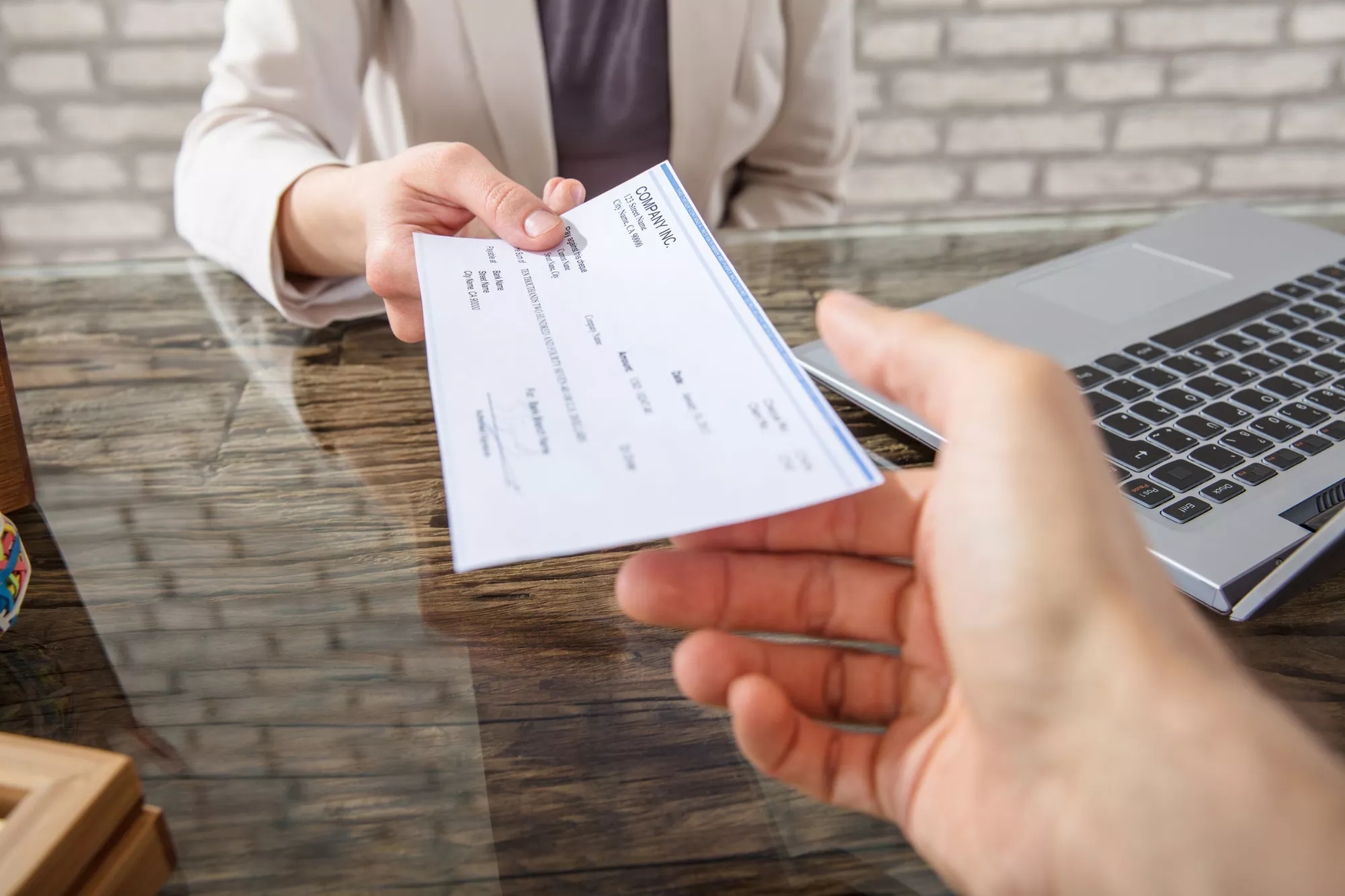 A person handing over a check to another person. A person handing over a check to another person.