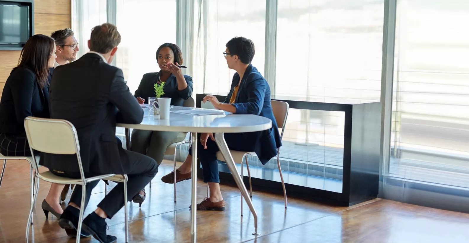 A team have a discussion in a modern, well lit meeting room. A team have a discussion in a modern, well lit meeting room.