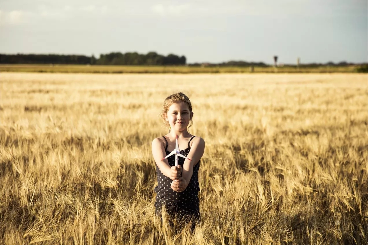 A smiling girl holding a pinwheel standing in a wheat field. A smiling girl holding a pinwheel standing in a wheat field.