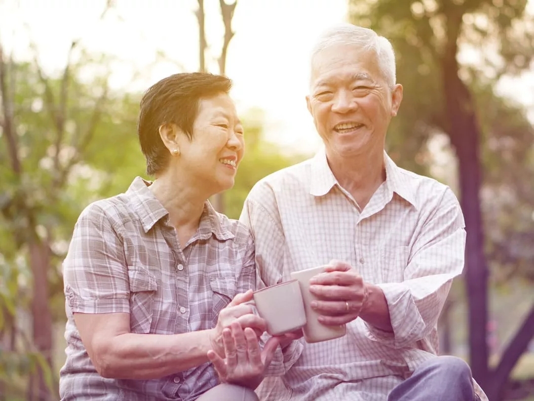 A man and a woman sitting and holding mugs in their hands and smiling. A man and a woman sitting and holding mugs in their hands and smiling.