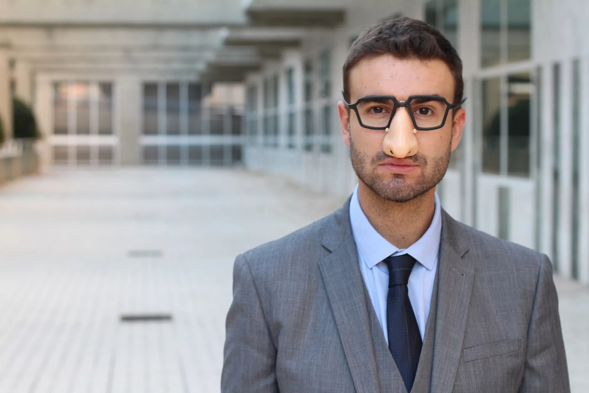 A person wearing suit and black glasses and an eyeglasses with fake nose. A person wearing suit and black glasses and an eyeglasses with fake nose.