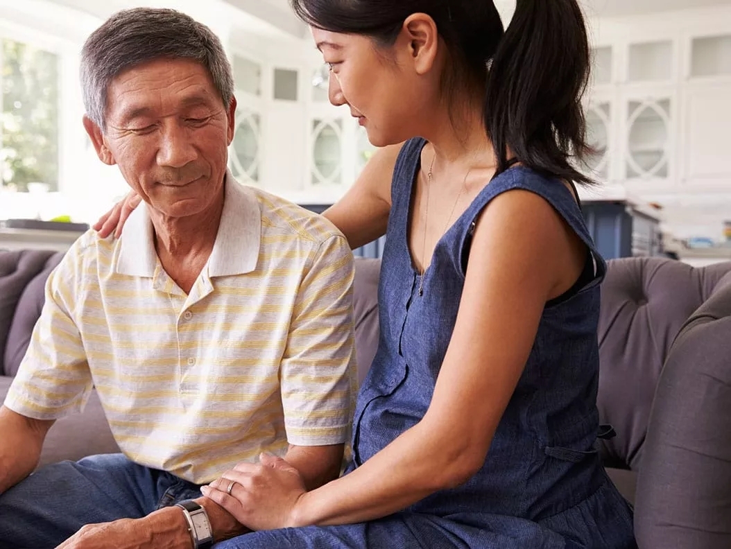 A woman and an older man sitting together on the couch. A woman and an older man sitting together on the couch.