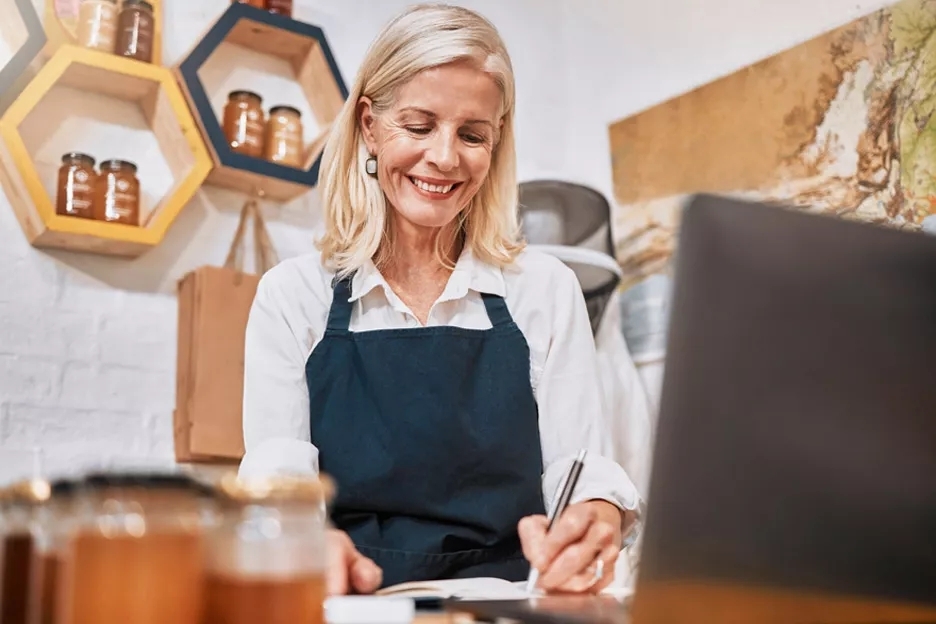 Business owner in front of laptop taking notes. Business owner in front of laptop taking notes.